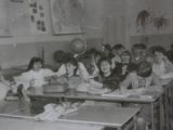 Czarno-białe zdjęcie. Uczniowie klasy IV liceum siedzą w ławkach szkolnych. Na ławce stoi globus. Na ścianie wiszą dwie mapy.