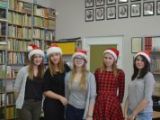 Pięć uczennic liceum stoi w rzędzie. Każda na głowie ma czerwoną czapkę św. Mikołaja. W tle regały z książkami.