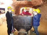 Pięcioro uczniów klas V-VIII w żółtych kaskach stoi przy wagonie w kopalni soli.