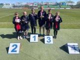 Grupa uczniów szkoły podstawowej z medalami na szyjach stoi boisku sportowym