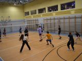W sali gimnastycznej uczniowie liceum w strojach sportowych grają w siatkówkę.